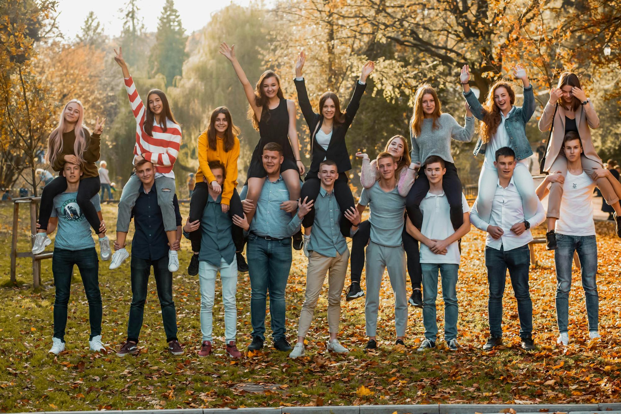 A large group of teenagers standing together outdoors in a park on an autumn day. Stock photograph; the people shown are not associated with PKD Bridge.